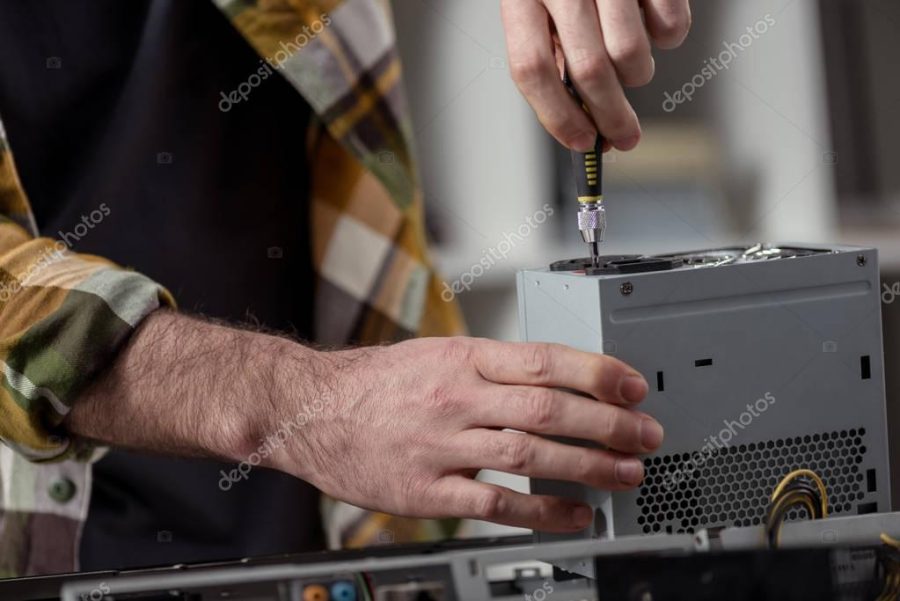 man using screwdriver while fixing computer detail