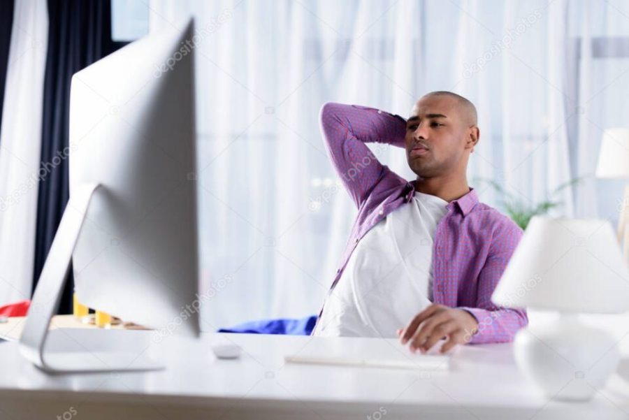 tired african american man looking at computer at home