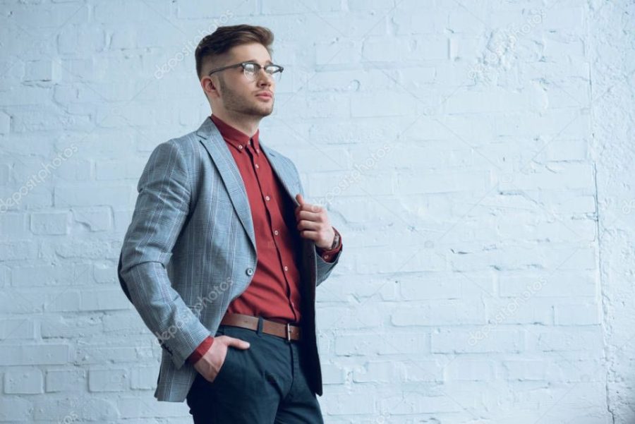 Stylish man in casual clothes wearing glasses by brick wall