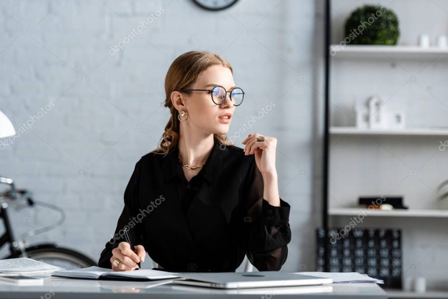 beautiful businesswoman in black clothes and glasses sitting on chair and whiting in note
