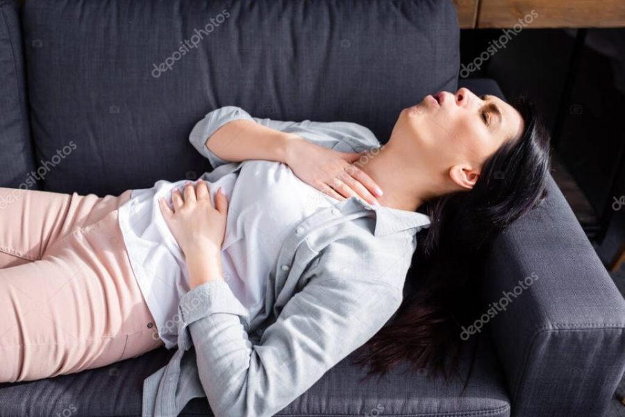 asthmatic woman coughing while lying on sofa