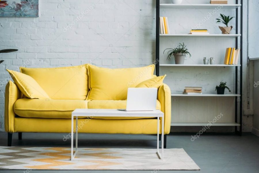 laptop on table near yellow sofa in living room