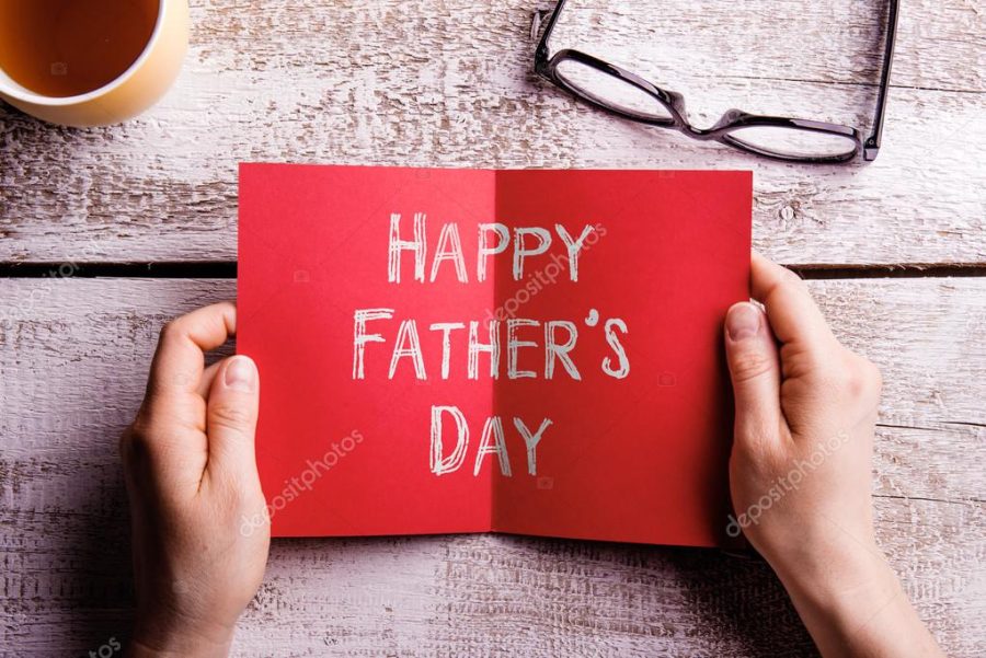 Fathers day composition. Hands of dad holding greeting card