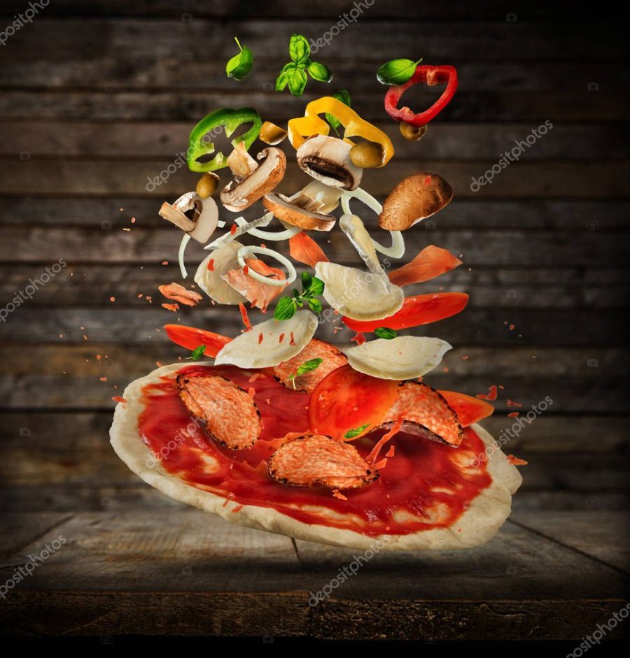 Flying ingredients with pizza dough, on wooden background