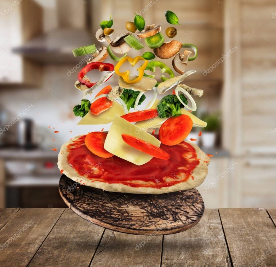 Flying pizza ingredients, served on wooden table