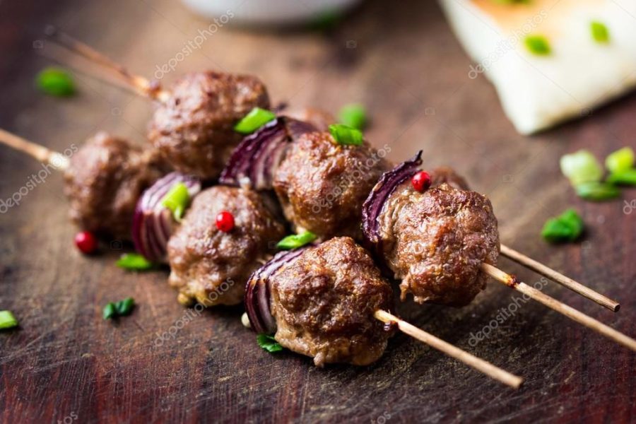 Meat kebab, beef balls on skewer with onions, sauce guacamole