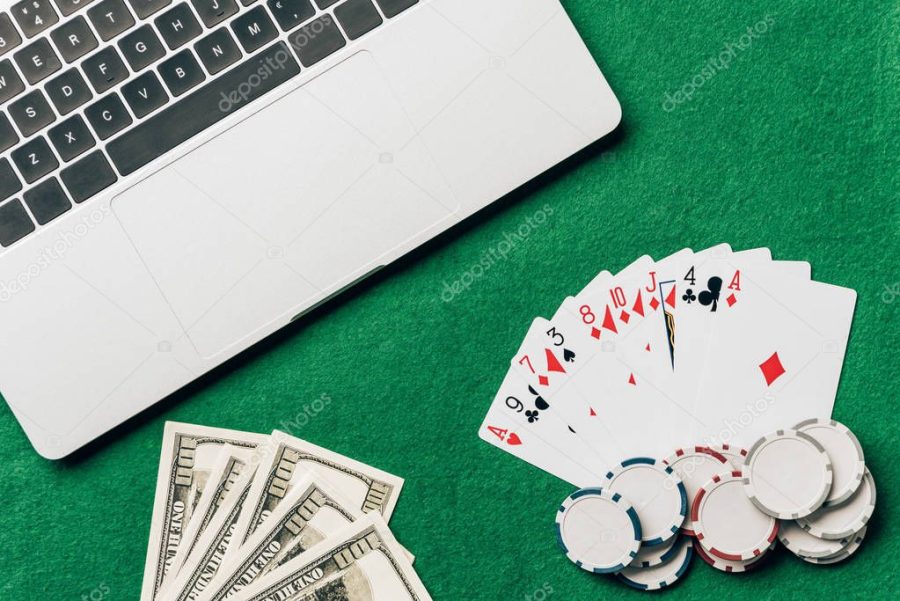 Online gambling concept with cards and money on table by laptop