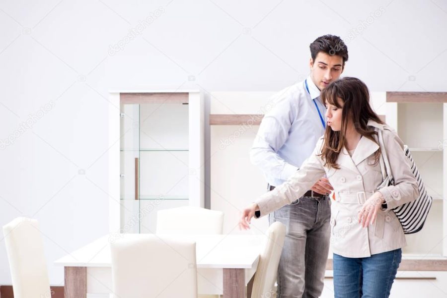 Salesman explaining to woman customer at furniture store