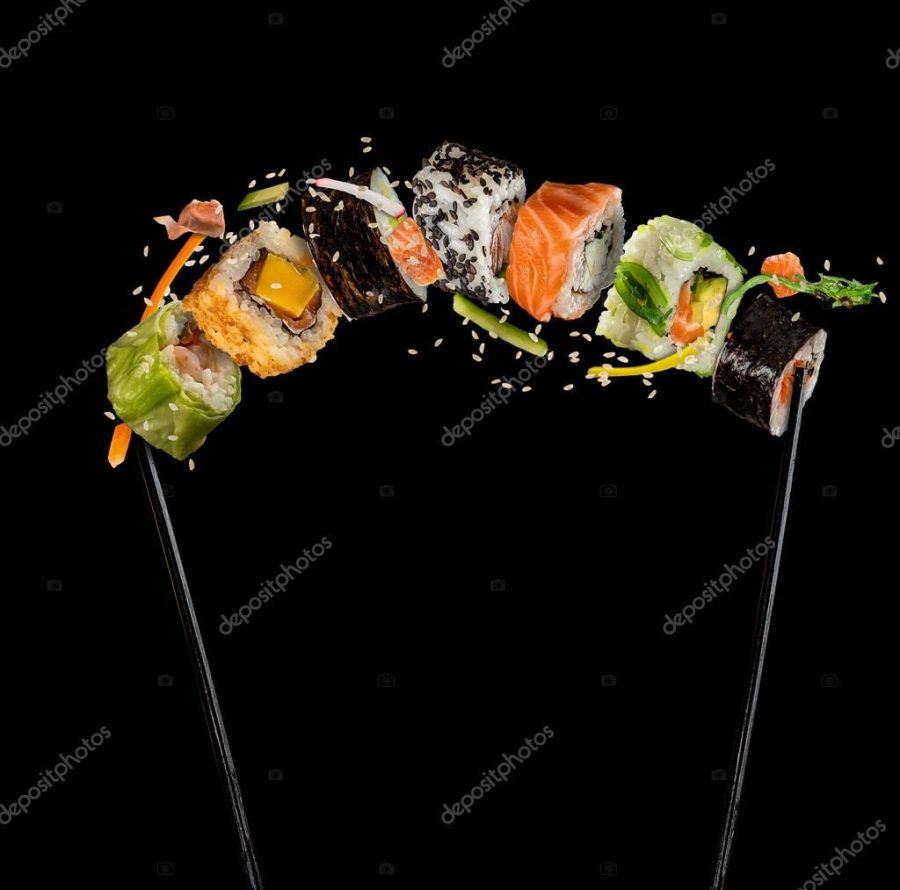 Sushi pieces placed between chopsticks on black background