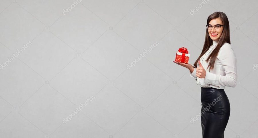 The brunette girl in a shirt and skirt with a gift in hands.