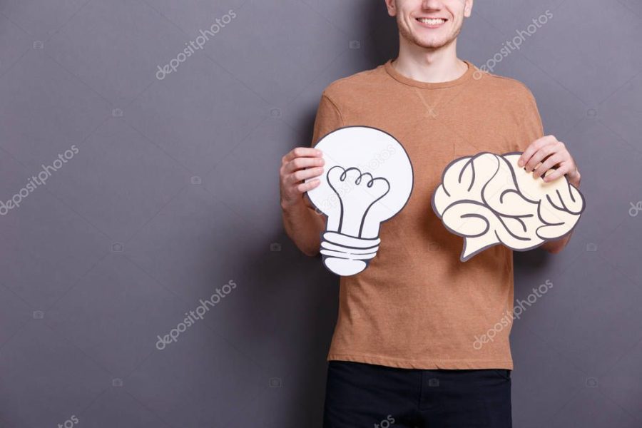 Young man holding paper brain and lamp bulb on gray background. Concept of ideas