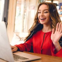 cheerful blogger waving hand while having video call on laptop