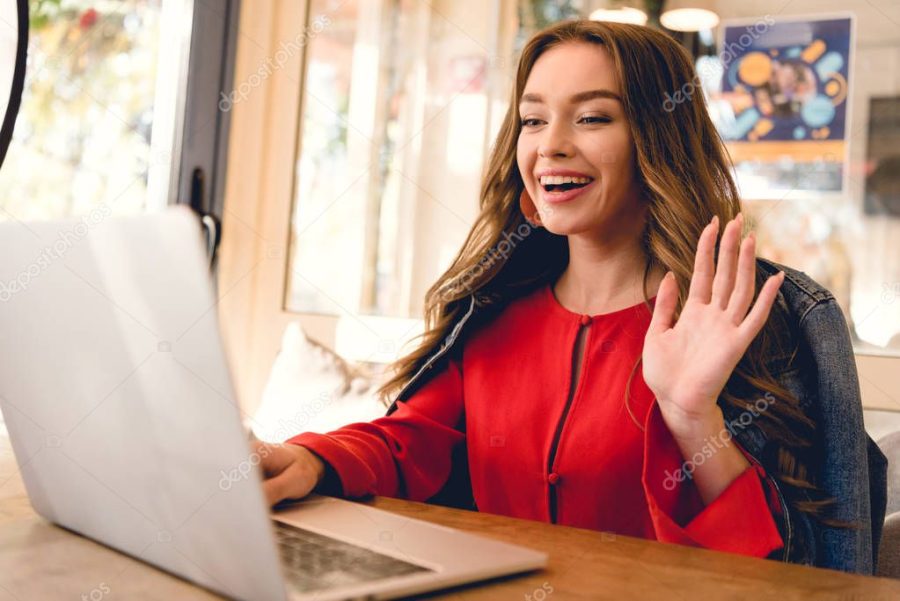 cheerful blogger waving hand while having video call on laptop