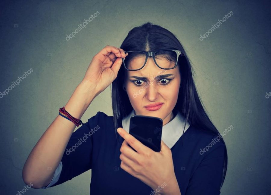 confused woman with glasses having trouble seeing cell phone