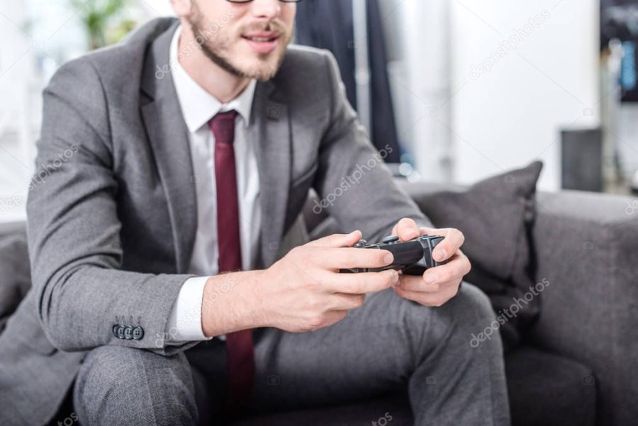 cropped view of businessman holding console and playing video game at home