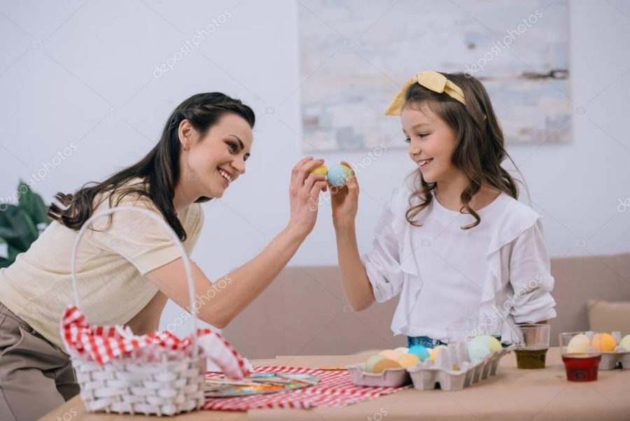 happy young mother and daughter doing egg tapping on easter