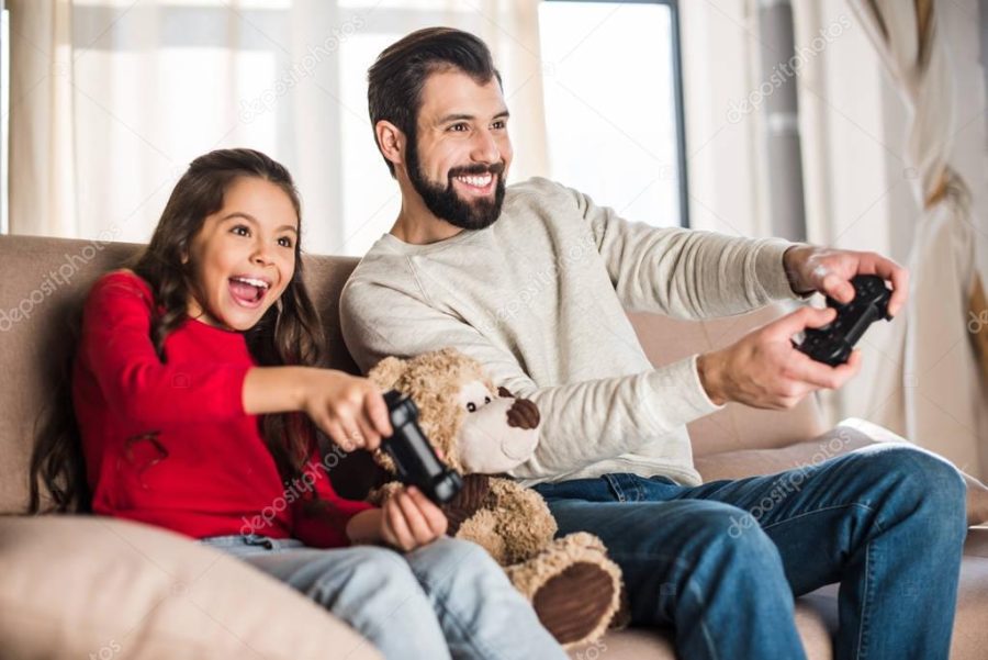 smiling father and daughter playing video game at home