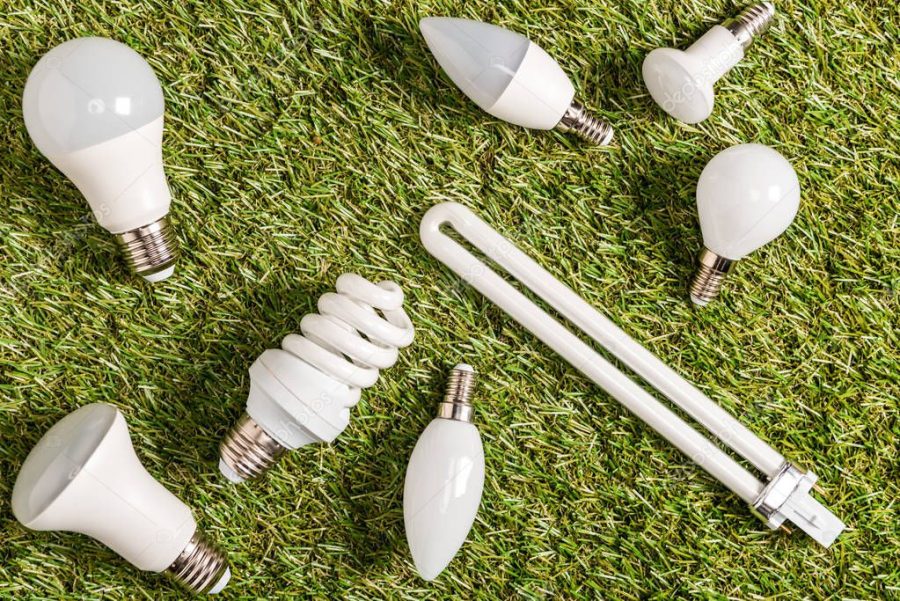 top view of fluorescent lamps on green grass, energy efficiency concept