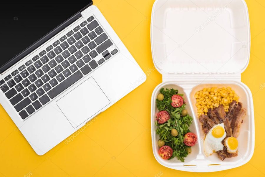 top view of laptop and eco package with corn, meat, fried eggs and salad isolated on yellow