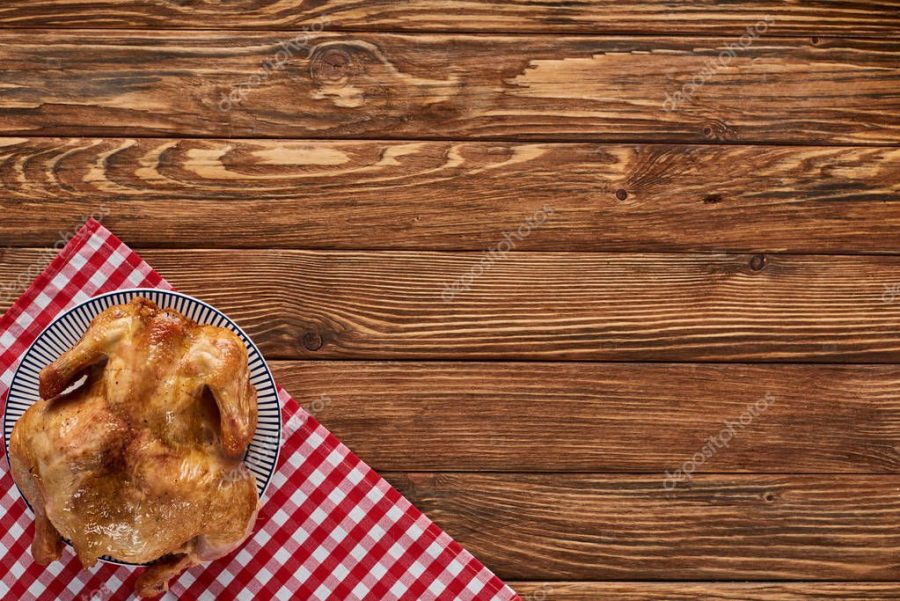 top view of roasted turkey on red plaid napkin served on wooden table