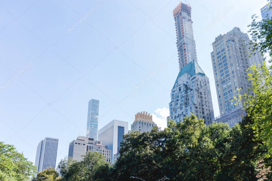 urban scene with trees in city park and skyscrapers in new york, usa