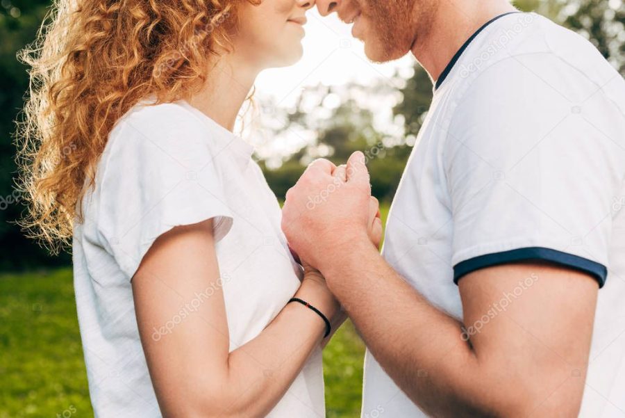 cropped shot of young couple in love holding hands at park