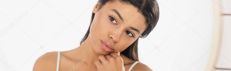 thoughtful young african american woman looking in mirror on white background, banner