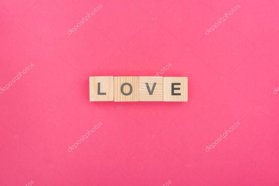 top view of love lettering made of wooden blocks on pink background