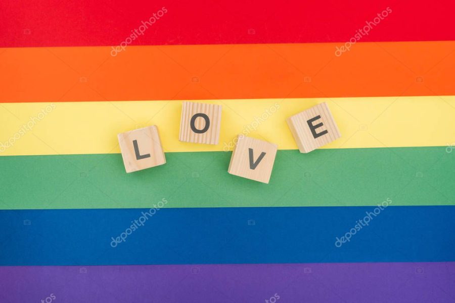 top view of love lettering made of wooden cubes on paper rainbow background