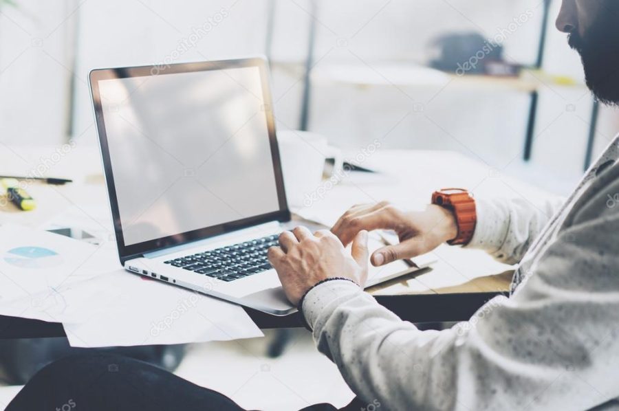 Photo bearded project manager working new startup modern loft. Using contemprary laptop with reflections screen on wood table. Creative idea process. Blurred background, film effect, horizontal