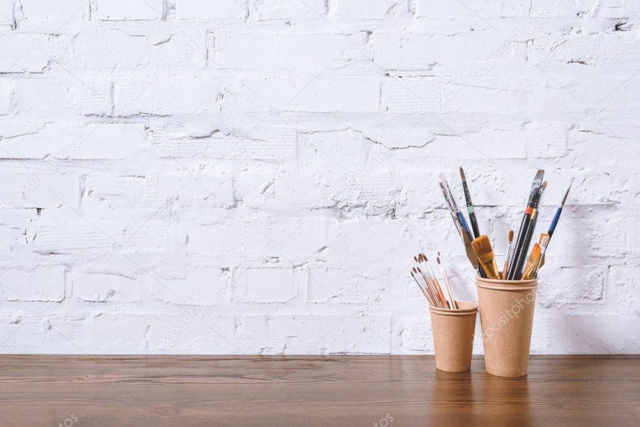 paint brushes in paper cups on white wall