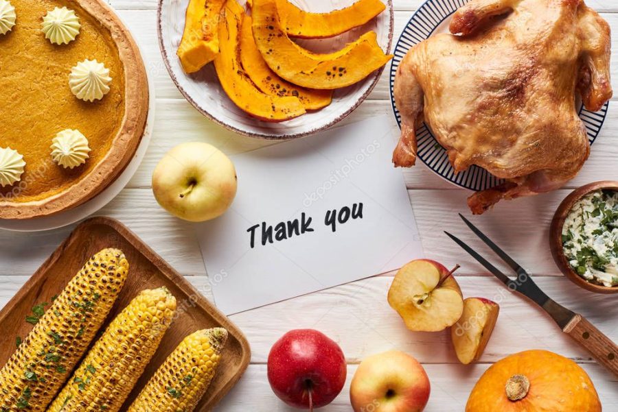 top view of roasted turkey, pumpkin pie and grilled vegetables served on white wooden table near thank you card