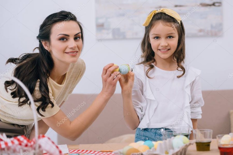 young mother and daughter doing egg tapping on easter