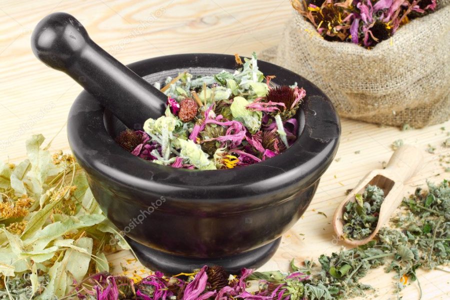 Mortar and pestle and sack with healing herbs on wooden table