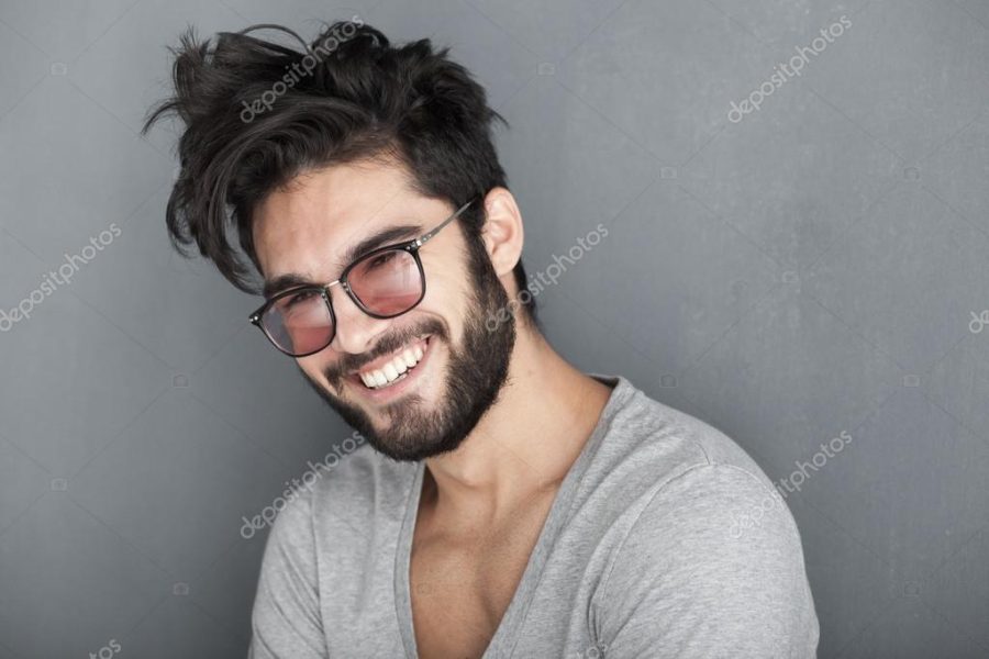 Sexy man with beard smiling big against wall