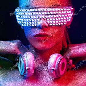 Beautyful girl with glitter and sparkles on her face and body. Portrait of sexy TDJ with headphones and neon sunglasses