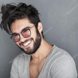 Sexy man with beard smiling big against wall