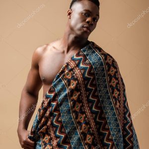 sexy naked tribal afro man covered in blanket posing isolated on beige