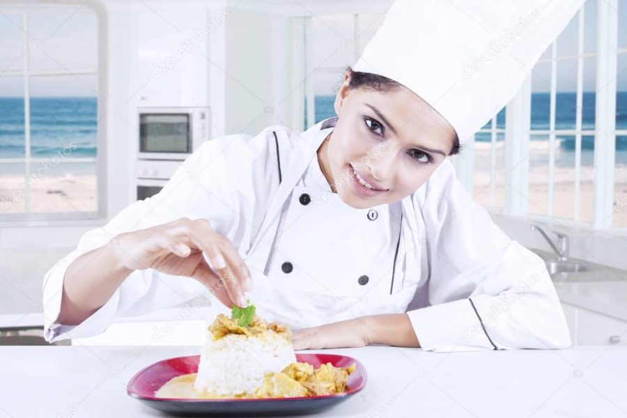 Indian chef decorating food in the kitchen