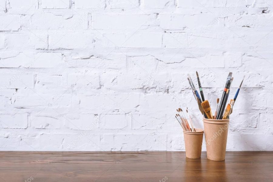 paint brushes in paper cups on white wall