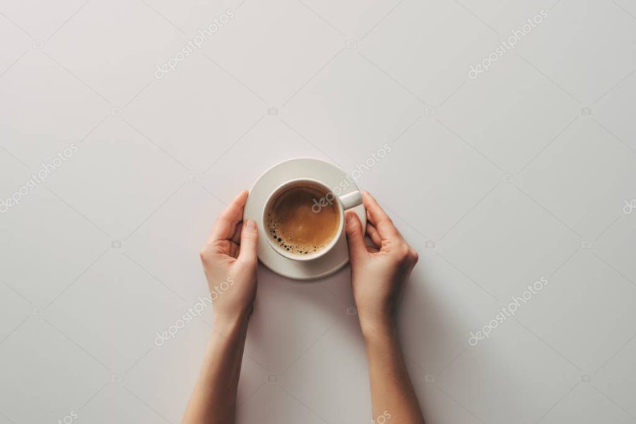 top view of female hands and cup of coffee with saucer on grey