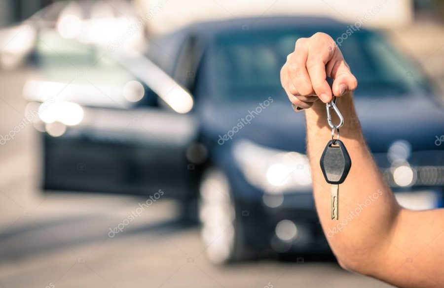 Man's hand holding modern car keys ready for rental - Concept of transportation with automobile second hand sale and trade