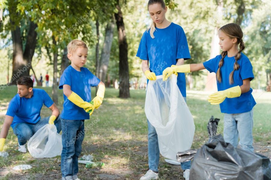 family collecting rubbish into recycled bags in forest, ecology concept