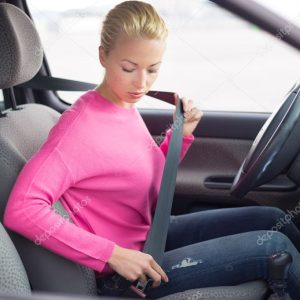 Beautiful woman fastening seat belt.