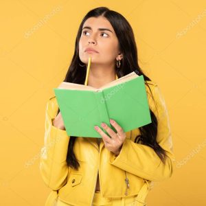 beautiful student thinking while holding pencil and book, isolated on yellow