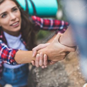 man helping girlfriend to climb rock